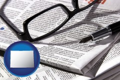 colorado map icon and a newspaper, with reading glasses and fountain pen